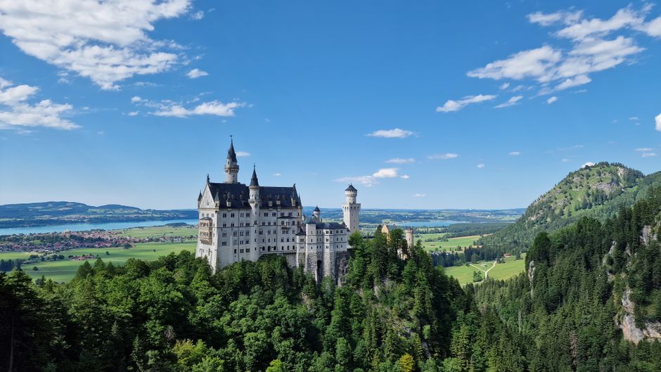 Stunning aerial view of Neuschwanstein Castle in Bavaria, Germany, surrounded by lush greenery.